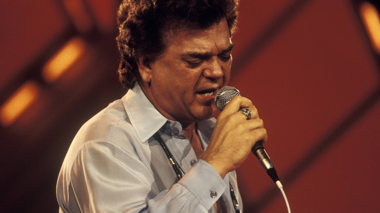 Conway Twitty singing emotionally into a microphone