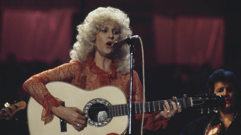 Tammy Wynette sitting and playing the guitar on stage