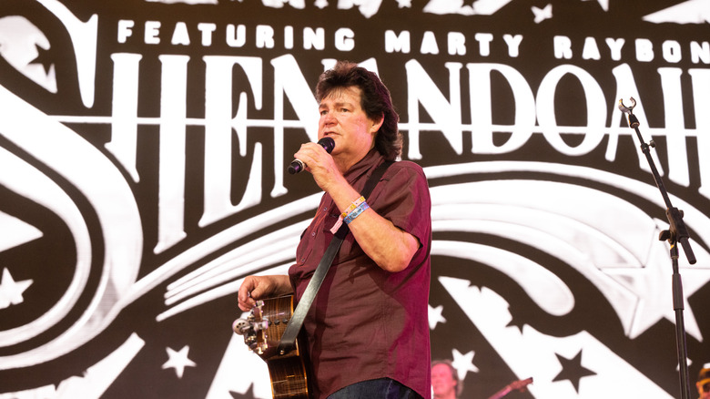 Marty Raybon on stage in front of a banner reading Shenandoah