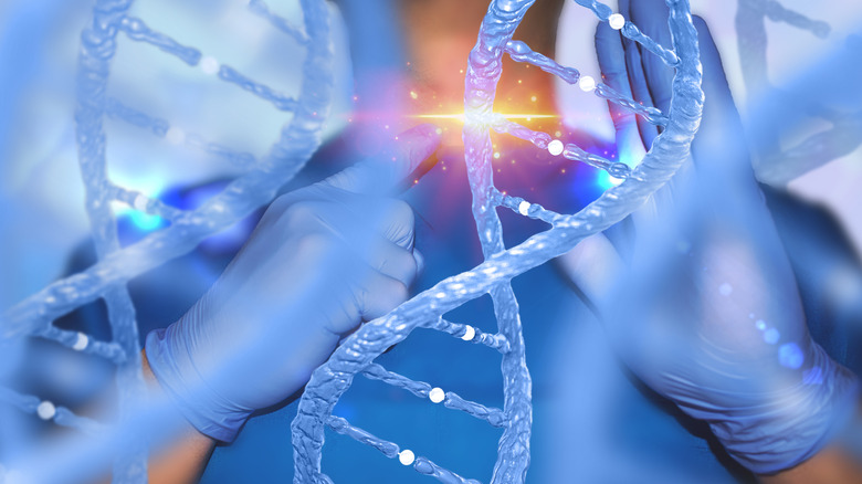 A gloved hand pointing to a strand of DNA