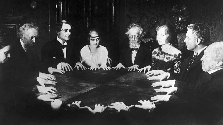 Group of people holding seance at round table
