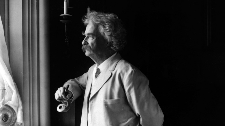 Mark Twain stands by window