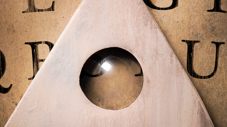 Planchette glides over Ouija board