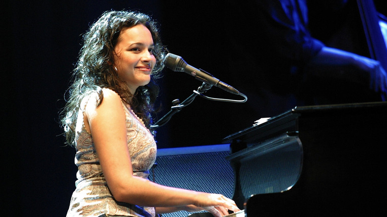 Norah Jones smiling and playing piano on stage