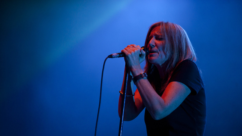 Portishead's Beth Gibbons singing into microphone against blue background