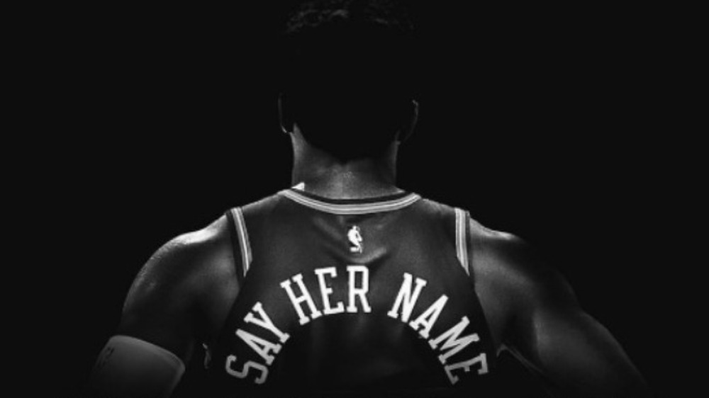 back of Donovan Mitchell with jersey that says, "say her name"