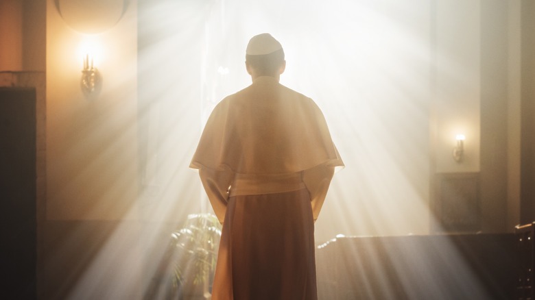 Clergyman standing in sun rays