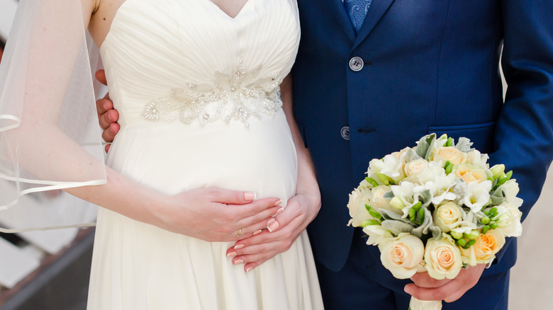 pregnant bride and groom posing