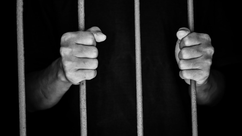 man holds onto jail bars
