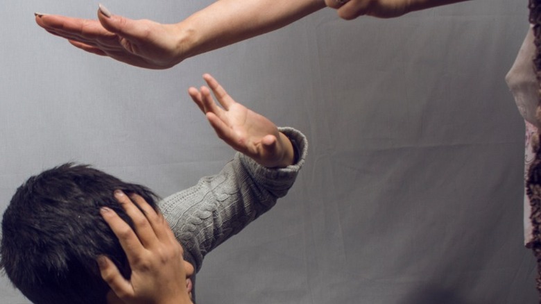 mom hits boy shielding himself hands