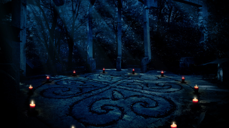 Circle of lit candles in a dark forest