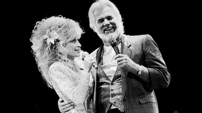 Black and white photo of Kenny Rogers and Dolly Parton from the 1980s, performing on stage