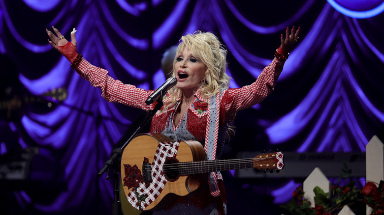 Dolly Parton onstage with guitar and microphone