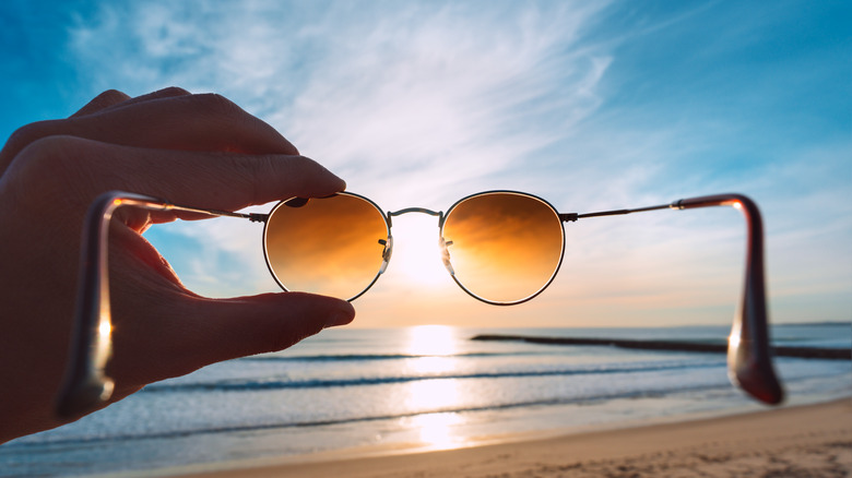 Sunglasses held up against sky on a beach