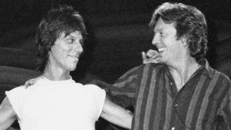 Jeff Beck and Eric Clapton smiling at each other on stage