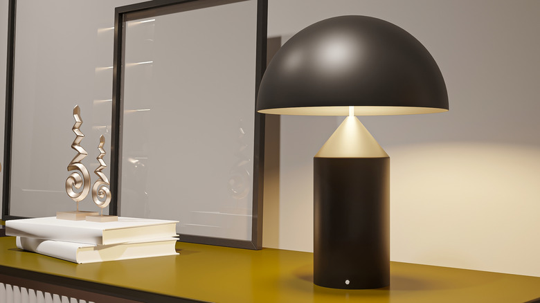 atollo table lamp beside mirror and stack of books