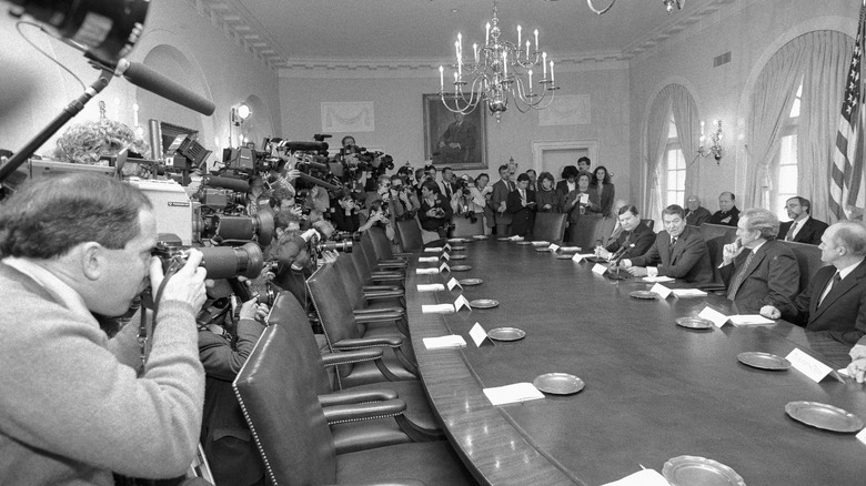 Ronald Reagan and his Iran-Contra review board surrounded by reporters and photographers
