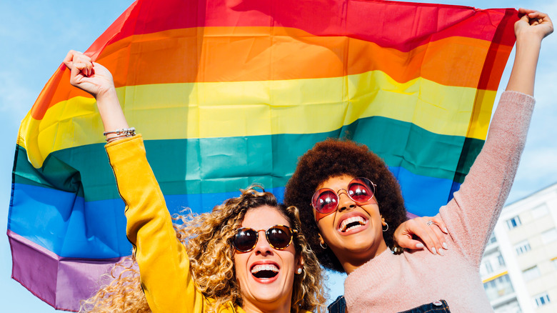 women flying LGBTQ+ pride flag