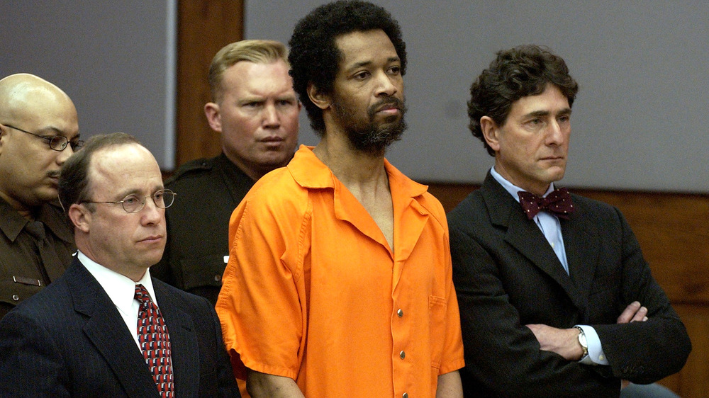 John Allen Muhammad in prison orange and attorneys standing in court