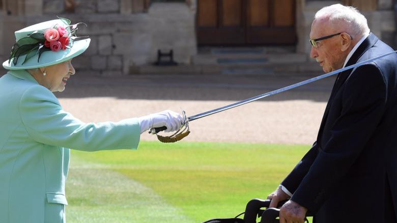 Queen Elizabeth putting a sword on a man's shoulder