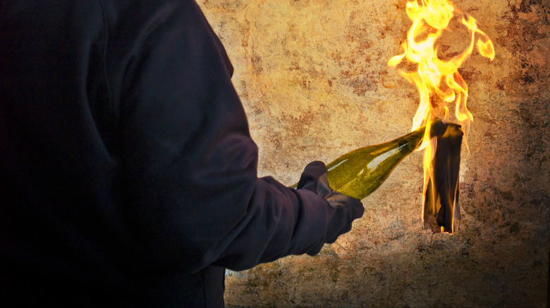 hooded person holding molotov cocktail