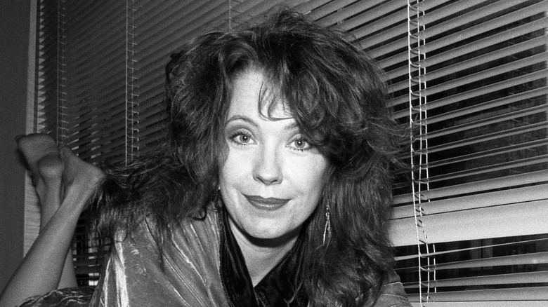 Pamela Des Barres smiling by blinds