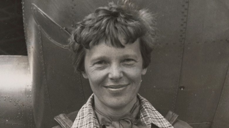 Amelia Earhart smiling in front of her plane