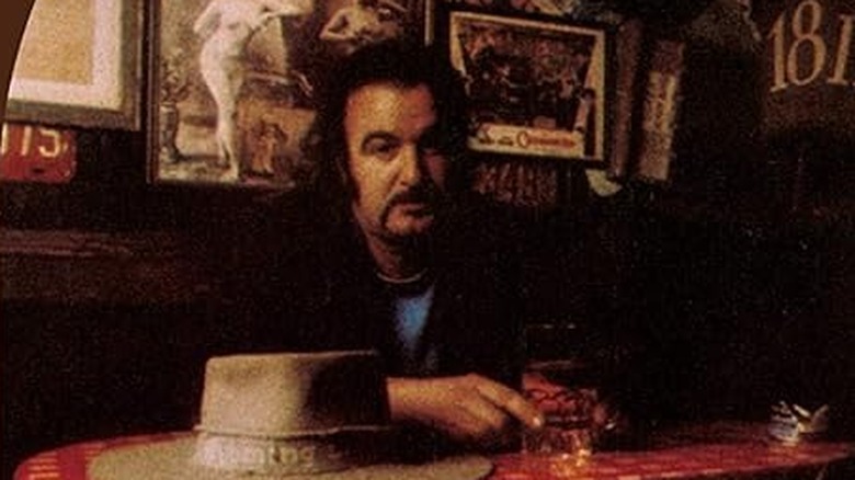 Jim Sullivan with moustache sat in pub with drink and hat on table