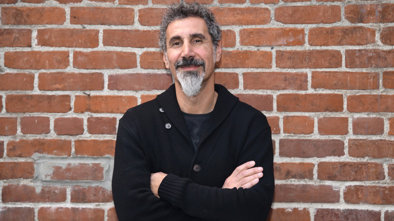 Serj Tankian of System of a Down poses in front of brick wall