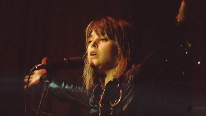 Suzi Quatro singing onstage with arms reached out