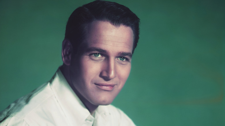 Paul Newman smirking in headshot on green background