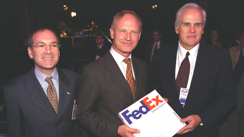 Fred Smith with two other men, holding a FedEx box