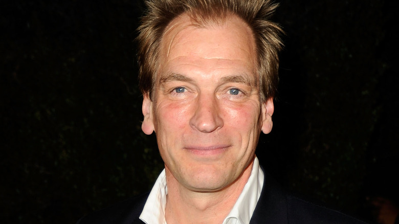 Julian Sands smiling black background