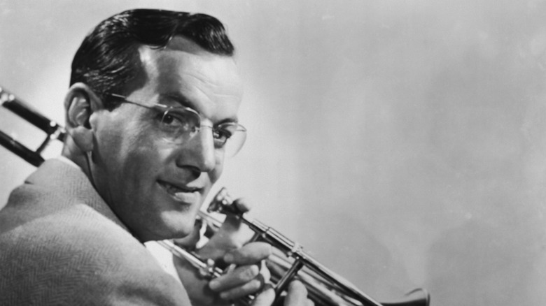 Glenn Miller looking over his shoulder holding a trombone