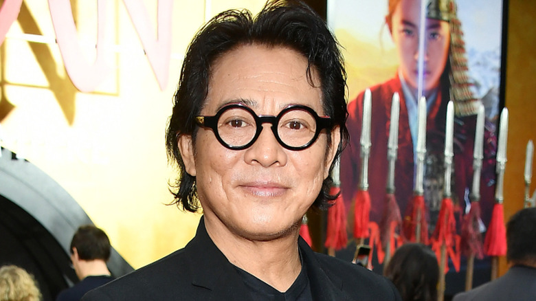 Jet Li smiling with closed lips and big glasses