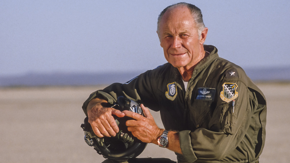 A picture of Chuck Yeager kneeling in an airfield around the 1980s.