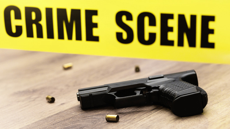 Pistol with shell casings and crime scene tape