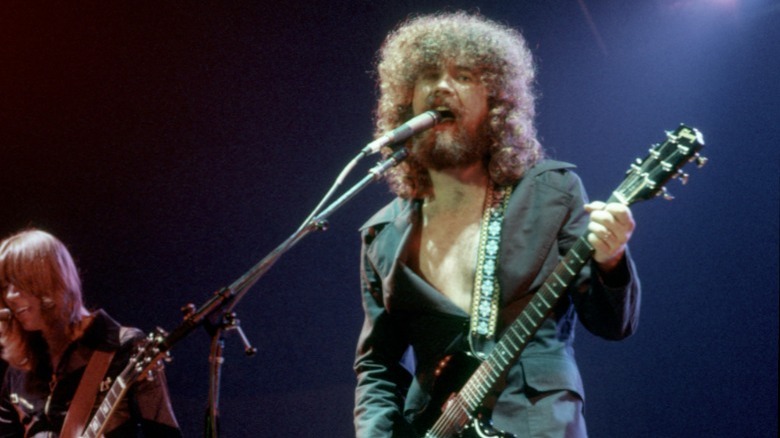 Brad Delp singing and playing guitar onstage