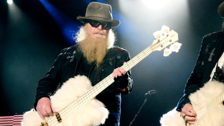Billy Gibbons playing a white fur-covered guitar onstage