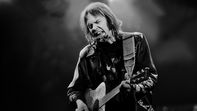 Black and white photo of Neil Young playing guitar