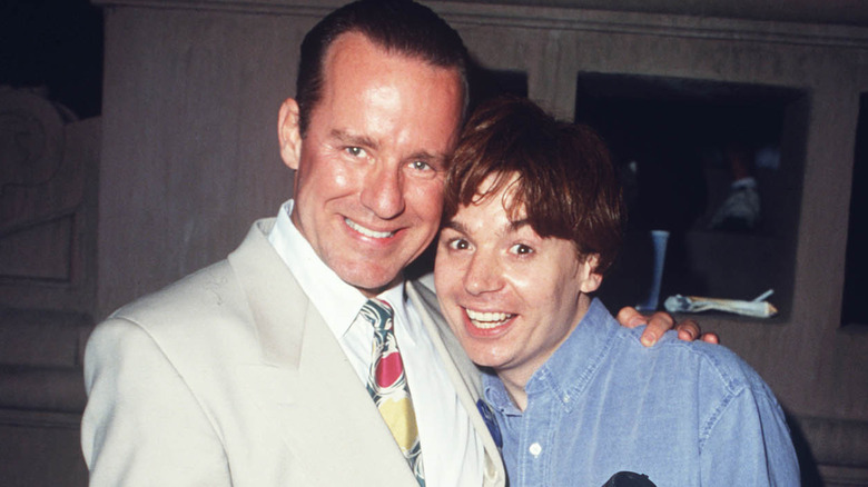 Phil Hartman and Mike Myers smiling and embracing