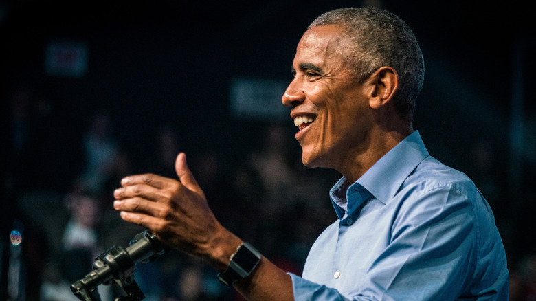 Barack Obama smiling and gesturing at a lectern