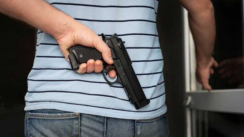 stock image of man with firearm behind his back