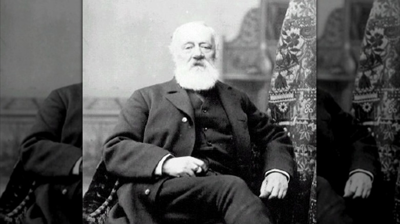 Antonio Meucci with white beard in dark suit sat posing for photo