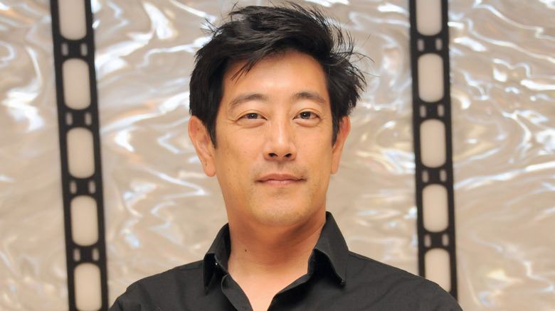 Grant Imahara posing in a black button down shirt with collar