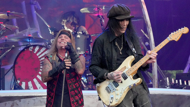 Mick Mars playing guitar onstage while Vince Neil sings