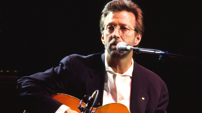 Eric Clapton plays acoustic guitar on stage