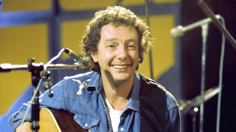 Fred Neil smiling with guitar on stage