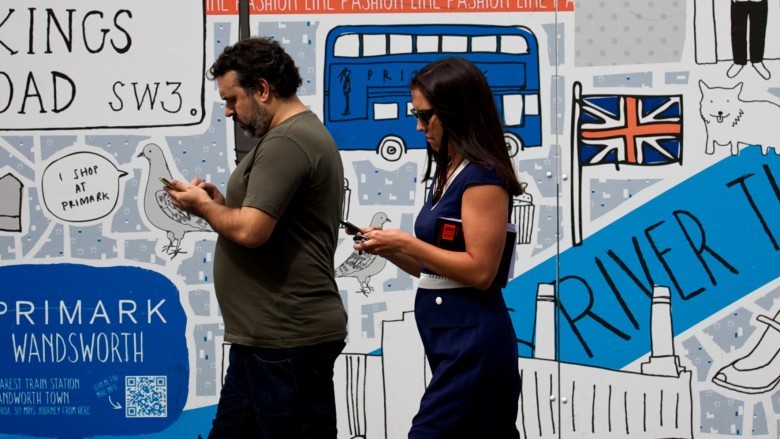 Two people walking while texting