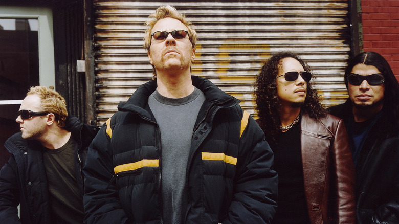 Metallica's Lars Ulrich, James Hetfield, Kirk Hammett, and Robert Trujillo standing in jackets and sunglasses
